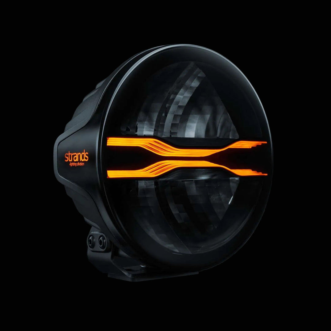 Black light fixture with amber accents on a dark background, featuring the Strands logo.