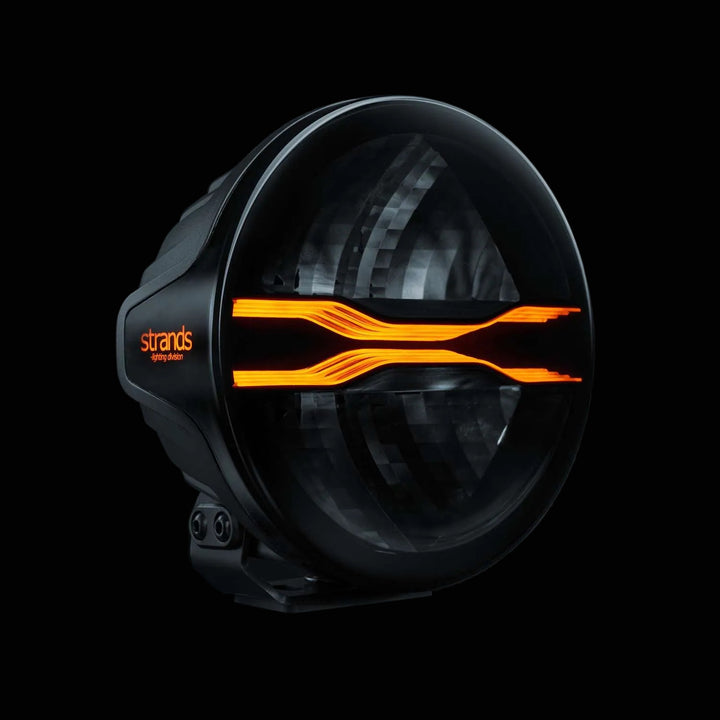Black light fixture with amber accents on a dark background, featuring the Strands logo.